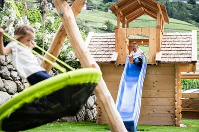 two children playing on a slide in a playground at Ölackererhof in Bressanone