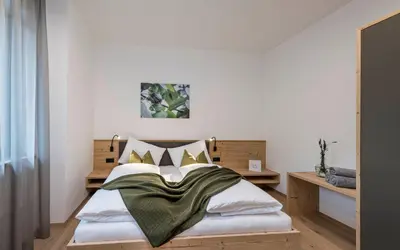 a bedroom with a bed with a green blanket on it at Ölackererhof in Bressanone