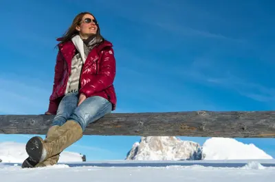 a woman sitting on a fence in the snow at Ferienwohnungen Koflerhof in Castelrotto
