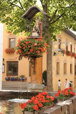 a fountain with flowers in front of a building at Ferienwohnungen Koflerhof in Castelrotto