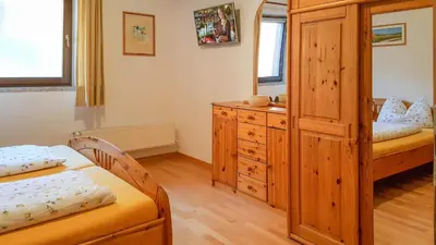 a bedroom with two beds and a wooden cabinet at Ferienwohnungen Koflerhof in Castelrotto