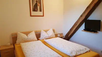 a bedroom with a bed with pillows and a tv at Ferienwohnungen Koflerhof in Castelrotto