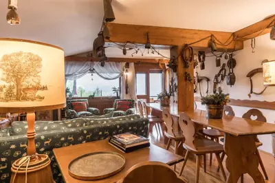 a living room with a couch and a table and chairs at Charming penthouse with breathtaking views in Cortina dʼAmpezzo