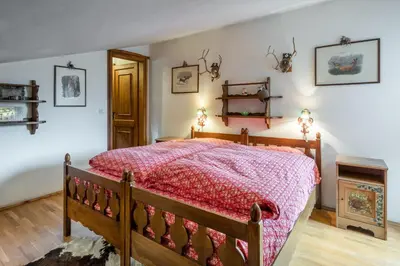a bedroom with a wooden bed with a red comforter at Charming penthouse with breathtaking views in Cortina dʼAmpezzo
