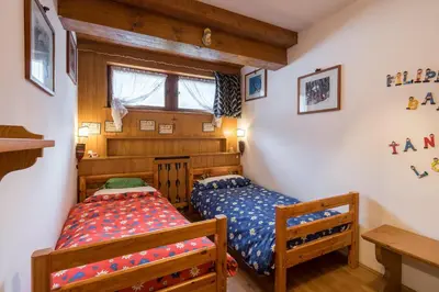 two twin beds in a room with wooden walls at Charming penthouse with breathtaking views in Cortina dʼAmpezzo