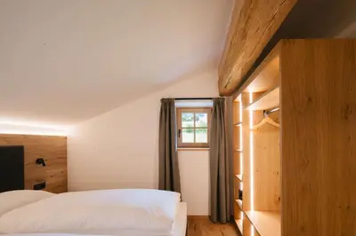 a bedroom with a white bed and a window at Schulmeisterhof in Kastelruth