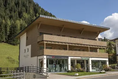 a building with a store in front of a mountain at Ciasa Vilin in Corvara in Badia