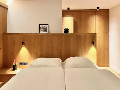 a bedroom with two white beds and a wooden headboard at Egger 5 in Sorafurcia