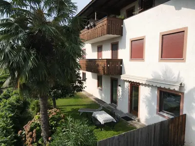 an apartment building with a palm tree and a bench at Plonhof Ferienwohnungen in Termeno