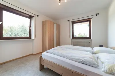 a bedroom with a large bed with two windows at Plonhof Ferienwohnungen in Termeno
