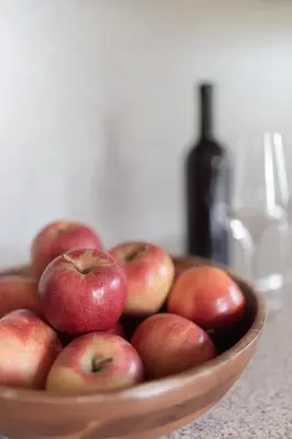 a bowl of apples on a table with a bottle of wine at Plonhof Ferienwohnungen in Termeno