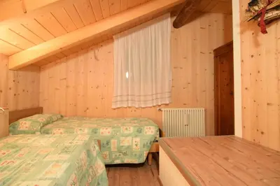 a bedroom with two beds and a window and a table at Tobià Gries in Canazei
