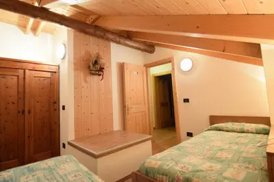 a bedroom with two beds and a wooden ceiling at Tobià Gries in Canazei