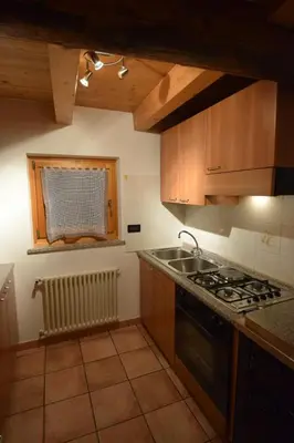 a kitchen with a stove and a sink and a window at Tobià Gries in Canazei