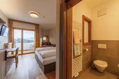 a bathroom with a bed and a toilet in a room at Pension Stern in Aldino