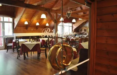 a restaurant with tables and chairs in a room with wooden ceilings at Appartaments Lavaredo in Carbonin