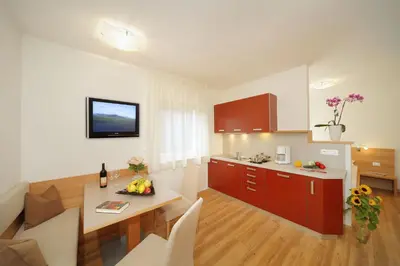 a kitchen with red cabinets and a table in a room at Ferienwohnungen Waldruhe in Santa Valburga St. Walburg