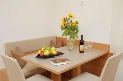 a table with a vase of flowers and a bottle of wine at Ferienwohnungen Waldruhe in Santa Valburga St. Walburg