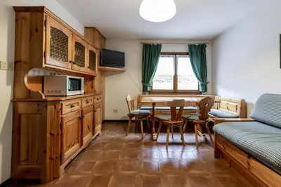 a room with a table and chairs and a kitchen at Stella Alpina in Campitello di Fassa
