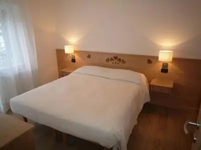 a bedroom with a white bed and two lights at Stella Alpina in Campitello di Fassa
