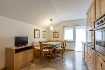 a kitchen with a table and a dining room with a television at Stella Alpina in Campitello di Fassa