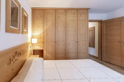 a bedroom with a large bed and wooden cabinets at Stella Alpina in Campitello di Fassa