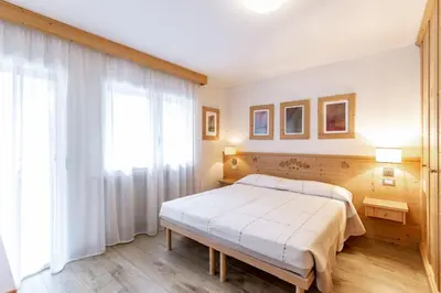 a bedroom with a bed and a large window at Stella Alpina in Campitello di Fassa