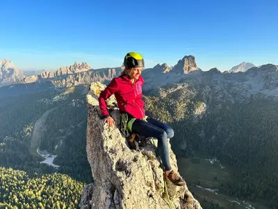 a woman sitting on the edge of a mountain at Climb house Geremia in Selva di Cadore