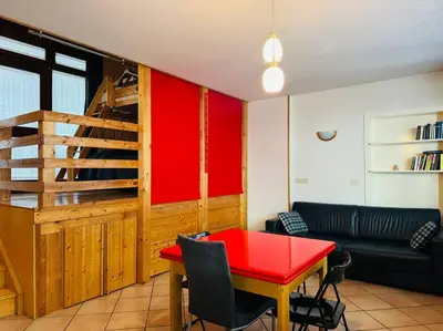 a living room with a red table and a couch at Appartamento nel cuore della Val di Fassa in Campestrin