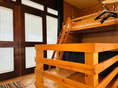 a wooden bunk bed in a room with windows at Appartamento nel cuore della Val di Fassa in Campestrin