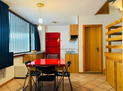 a kitchen with a red table and chairs at Appartamento nel cuore della Val di Fassa in Campestrin