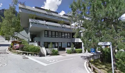 a building with a parking lot in front of it at Appartamento nel cuore della Val di Fassa in Campestrin
