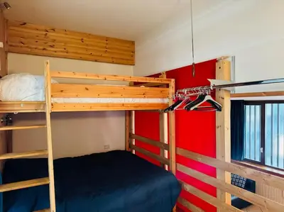 a bedroom with two bunk beds and a red wall at Appartamento nel cuore della Val di Fassa in Campestrin