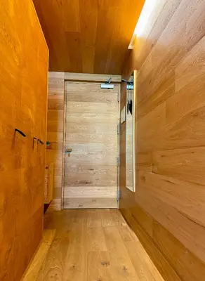 a walk in shower in a room with wooden walls at Die Bücherstube im living Kampill in Bolzano