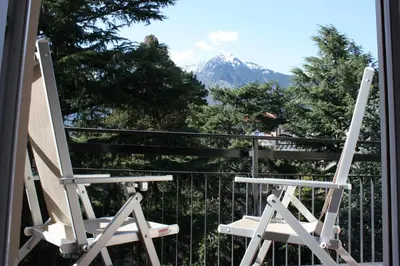 a white rocking chair sitting on a balcony with a mountain at Appartamento Adele in Merano