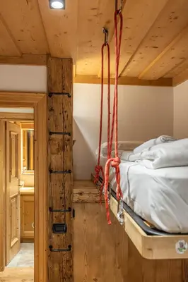 a bedroom with a bed with ropes hanging from the ceiling at Casa dell Alpinista a Cortina d Ampezzo in Cortina dʼAmpezzo