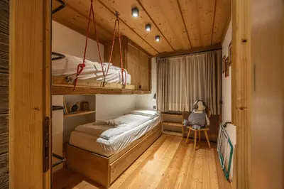 a small bedroom with a bunk bed and a chair at Casa dell Alpinista a Cortina d Ampezzo in Cortina dʼAmpezzo