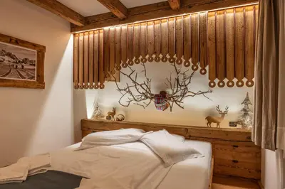 a bedroom with a bed and a antler chandelier at Casa dell Alpinista a Cortina d Ampezzo in Cortina dʼAmpezzo
