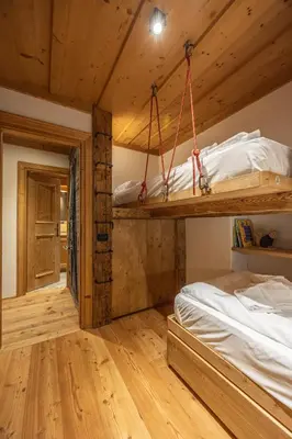 a bedroom with two bunk beds and wooden floors at Casa dell Alpinista a Cortina d Ampezzo in Cortina dʼAmpezzo
