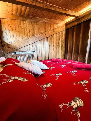 a bed with a red blanket and pillows in a room at Chalet vicino le piste da sci in Pocol