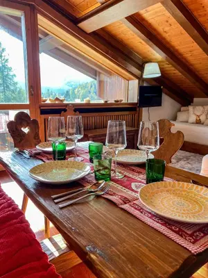 a wooden table with plates and wine glasses on it at Chalet vicino le piste da sci in Pocol