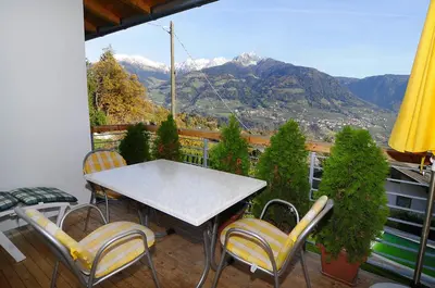 a table and chairs on a balcony with mountains at Haus Rosengarten in Tirolo