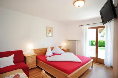a bedroom with a red bed and a red chair at Haus Rosengarten in Tirolo
