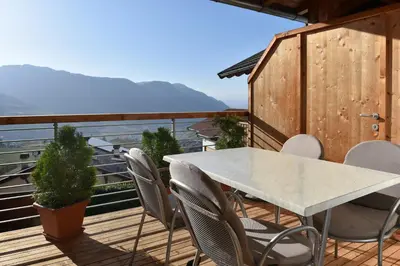 a white table and chairs on a deck with a view at Haus Rosengarten in Tirolo