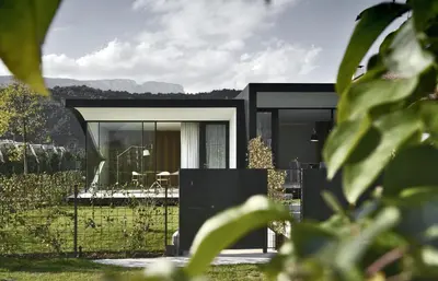 a black house with a view of a garden at Mirror Houses in Bolzano