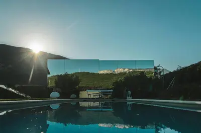 a reflection of the sun in a building with a pool at Mirror Houses in Bolzano