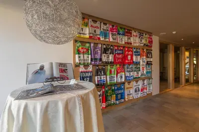 a table in a room with a wall of magazines at Mölgg Dolomites Residence in San Vigilio Di Marebbe