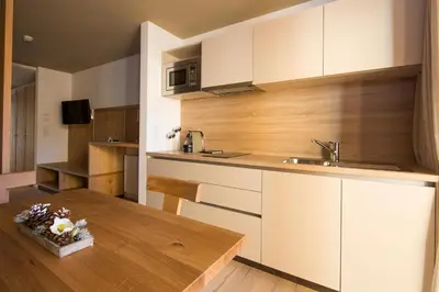 a kitchen with white cabinets and a wooden table at Mölgg Dolomites Residence in San Vigilio Di Marebbe