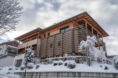 a wooden house in the snow with snow covered trees at Mölgg Dolomites Residence in San Vigilio Di Marebbe