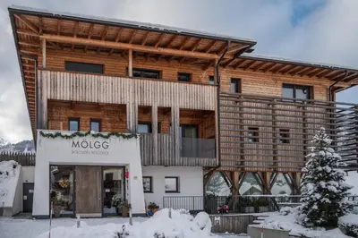 a large wooden building with a sign that reads moke at Mölgg Dolomites Residence in San Vigilio Di Marebbe